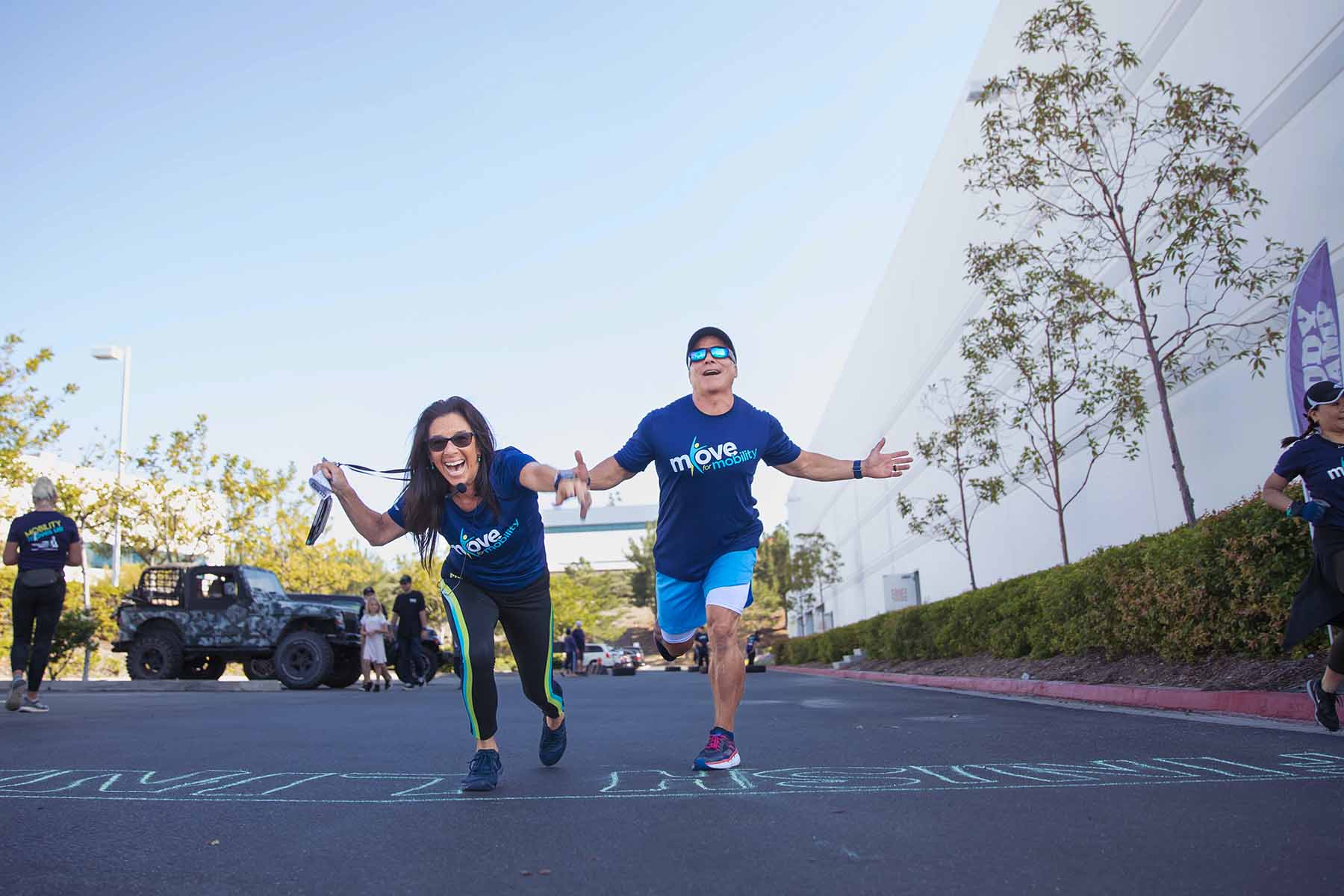 Two people racing to the finish line in Move for mobility branded T shirts