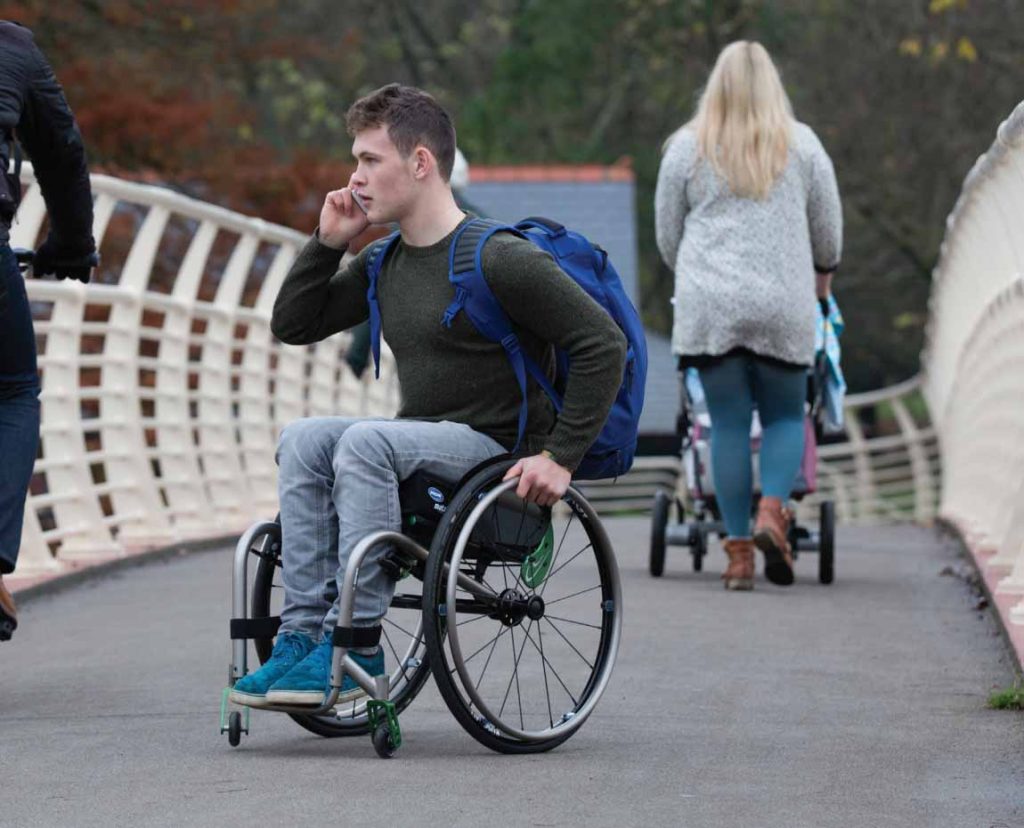 Image shows man in a wheelchair on a mobile device